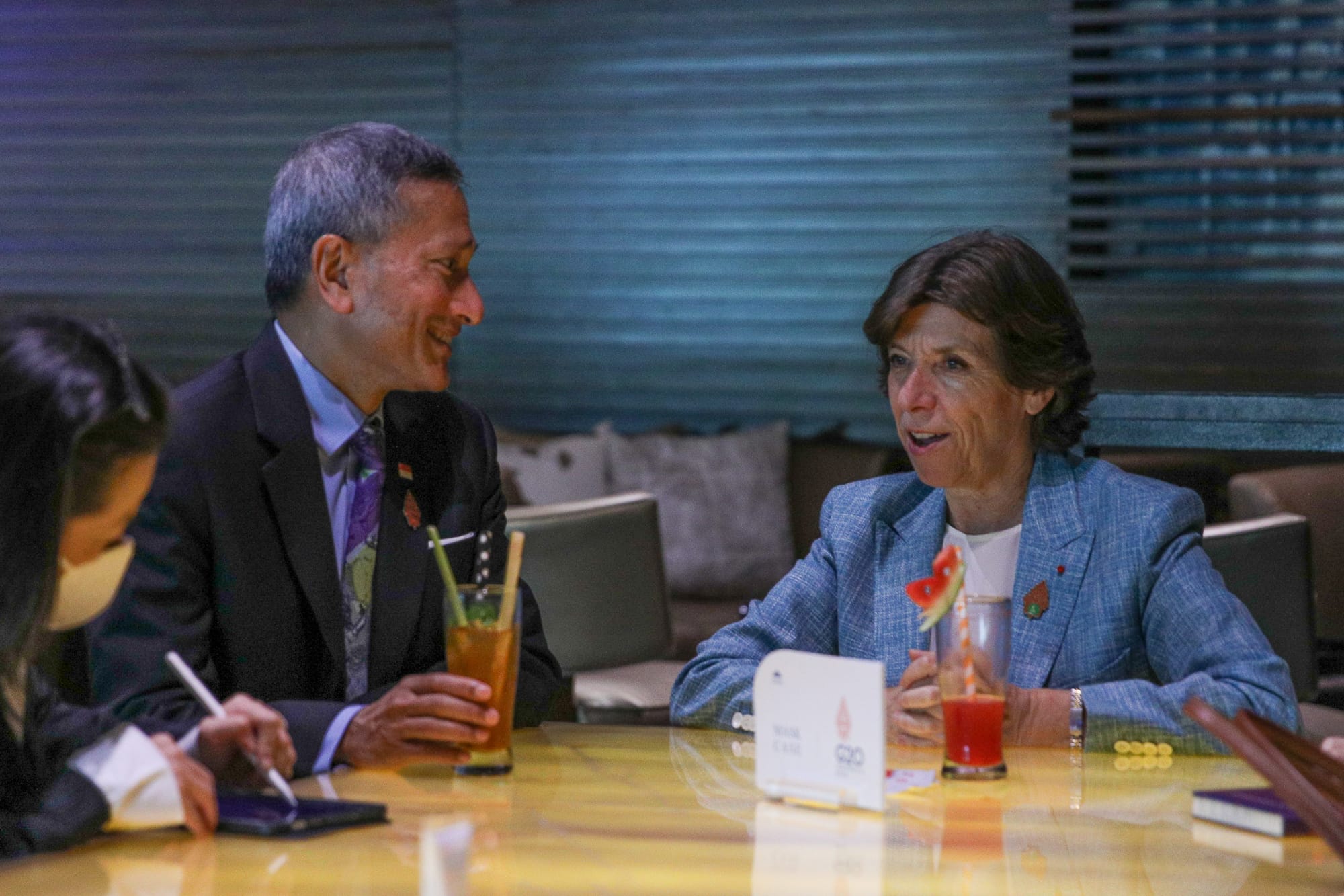 Three people wearing hijabs and lanyard, seated with laptops and tablets in a meeting.
